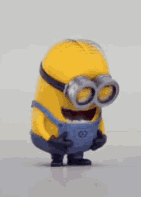a yellow minion wearing goggles and overalls is laughing .