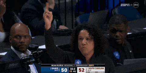 a woman holds up her hand while watching a basketball game on espn