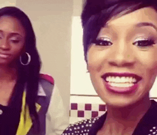 two women are standing next to each other and one is smiling .