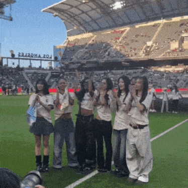 a group of girls are posing for a picture on a soccer field in front of a stadium that has the word zoo on it