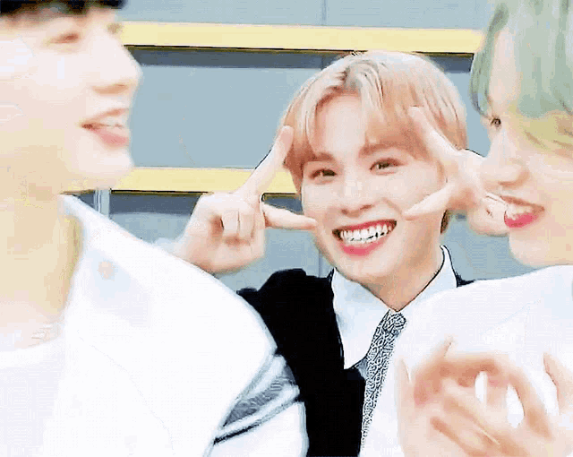 a group of young men are making funny faces with their hands while standing next to each other .