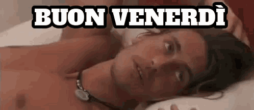 a man without a shirt is laying on a bed with the words buon venerdi written above him .