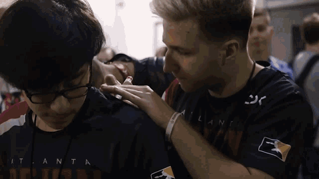 a man in an atlanta shirt is touching another man 's shoulder