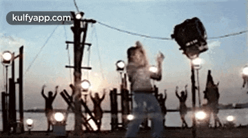 a boy is dancing in front of a group of people while a bucket is being lifted in the air .