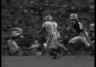a black and white photo of a football game with a player laying on the ground .