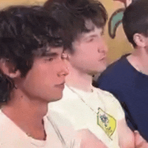 a group of young men are sitting next to each other in a room and looking at something .