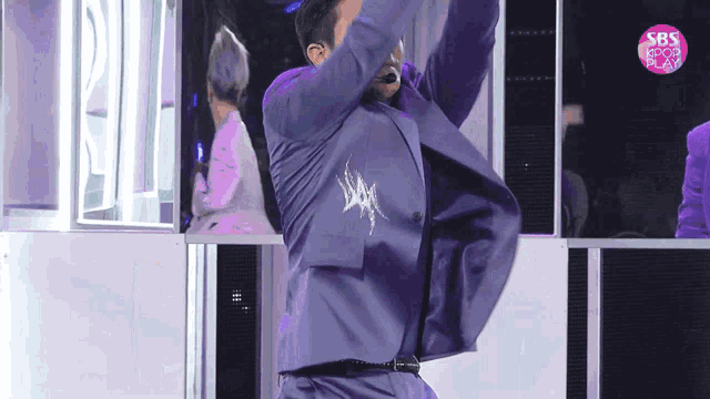 a man in a purple suit is dancing in front of a sbs sign