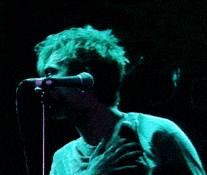 a man singing into a microphone with a green shirt