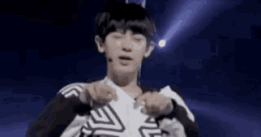 a young man in a black and white shirt is dancing on a stage .