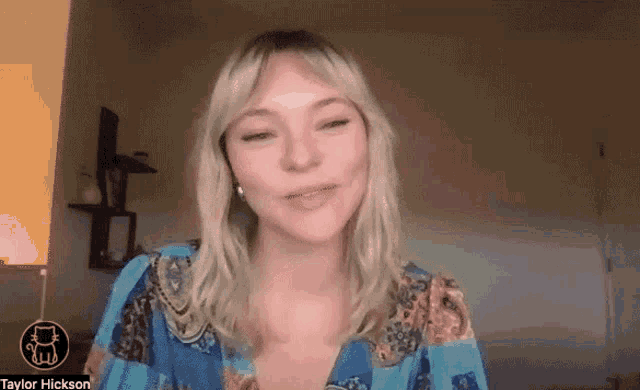 a woman in a blue shirt is talking on a video call with a cat .