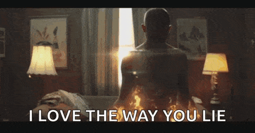 a man is sitting on a bed with a fire coming out of his chest and says `` i love the way you lie '' .