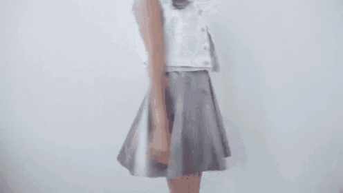 a woman in a white top and a silver skirt is dancing .