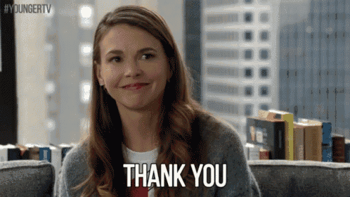 a woman is sitting on a couch smiling and saying thank you .