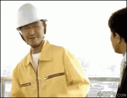a man wearing a hard hat and a yellow jacket talks to a woman