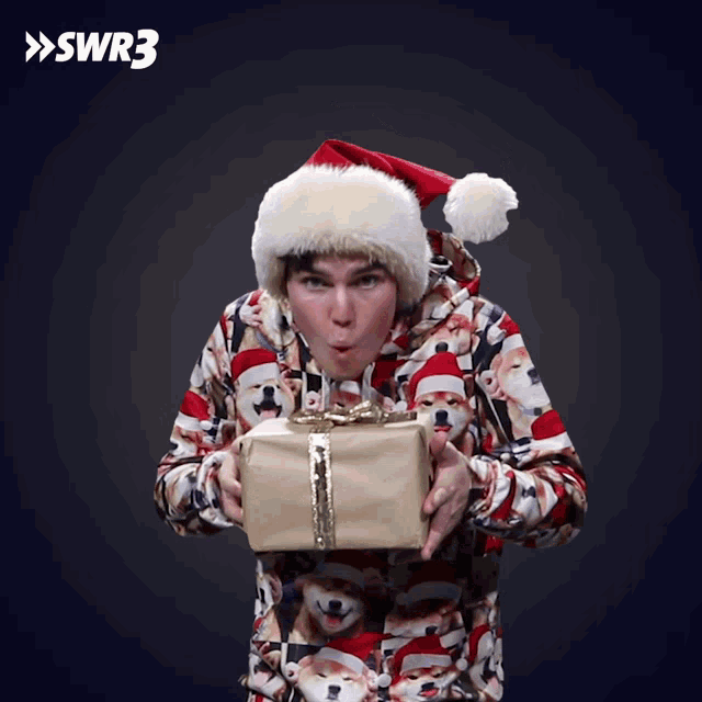a man wearing a santa hat is holding a gift in his hands
