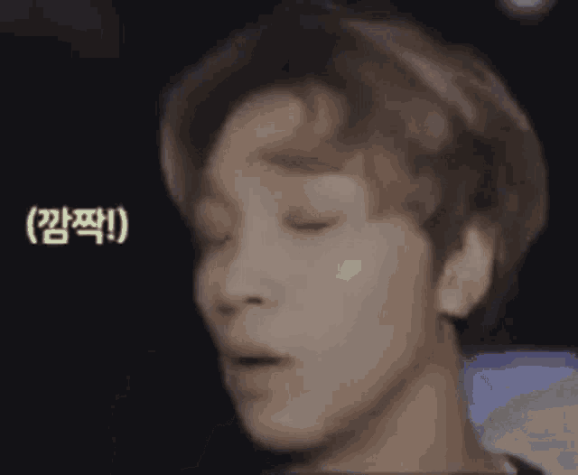 a close up of a person 's face with their eyes closed and a foreign language on the bottom .