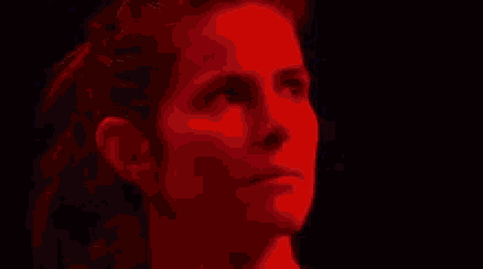 a close up of a woman 's face with a ponytail on a dark background .