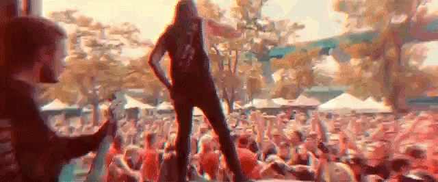 a man is standing on a stage playing a guitar in front of a crowd .