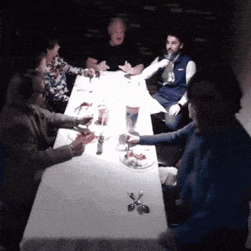 a group of people are sitting at a table with plates of food and a cup that says columbia on it