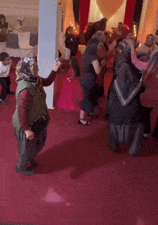 a group of people are dancing on a red carpeted floor