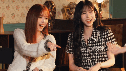 two women are laughing and pointing at something