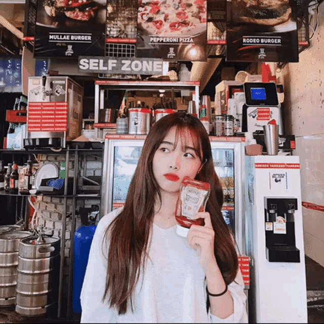 a girl holding a bottle of ketchup in front of a self zone sign
