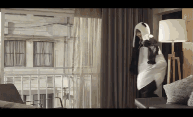 a person in a panda costume stands in a living room