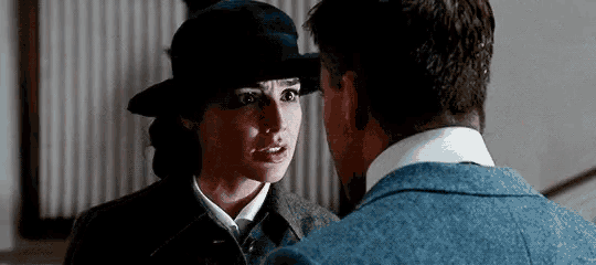 a man and a woman are looking at each other and the woman is wearing a hat