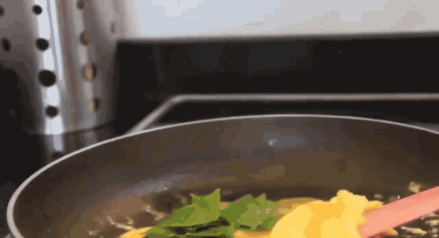 eggs are being cooked in a pan with a pink spatula