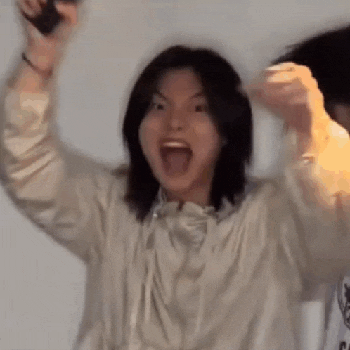 a woman with long black hair is holding a microphone in her hand and making a funny face .