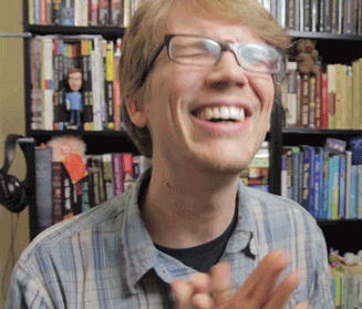 a man wearing glasses and a plaid shirt is smiling