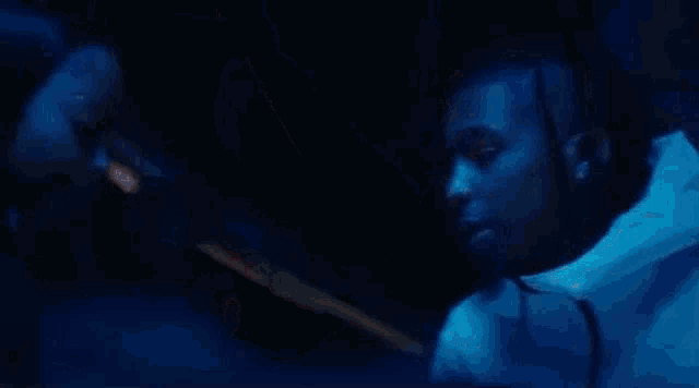a woman is smoking a cigarette in a dark room while a man looks on .