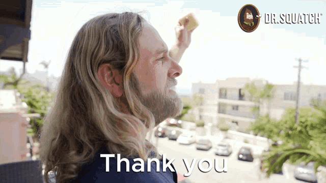 a man with long hair and a beard says thank you in front of a dr. squatch logo