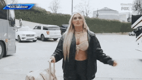 a woman is carrying a suitcase in a parking lot .