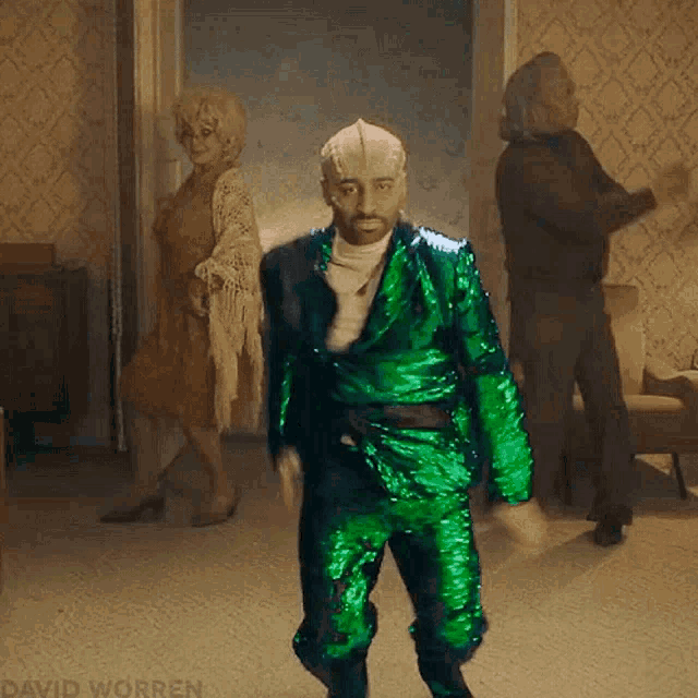 a man in a green suit is dancing in a room