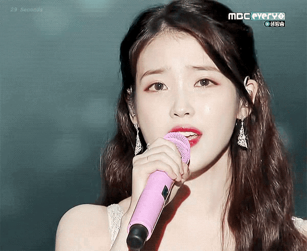 a woman singing into a pink microphone with mbc everyo on the bottom