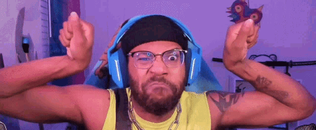 a man with a beard and glasses is wearing headphones and making a funny face