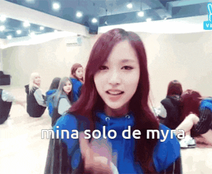 a girl in a blue hoodie says mina solo de myra in front of a group of girls