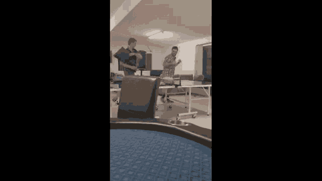 two men are playing ping pong in a room with a table .