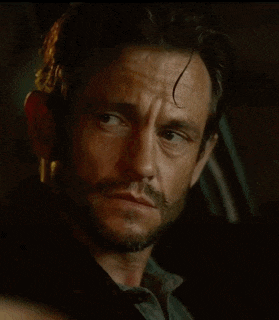 a close up of a man 's face with a beard in a dark room