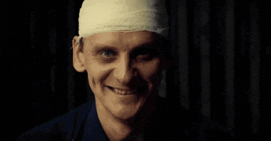 a man with a bandaged head smiles at the camera