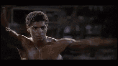 a man without a shirt is standing in a boxing ring with his fist in the air .