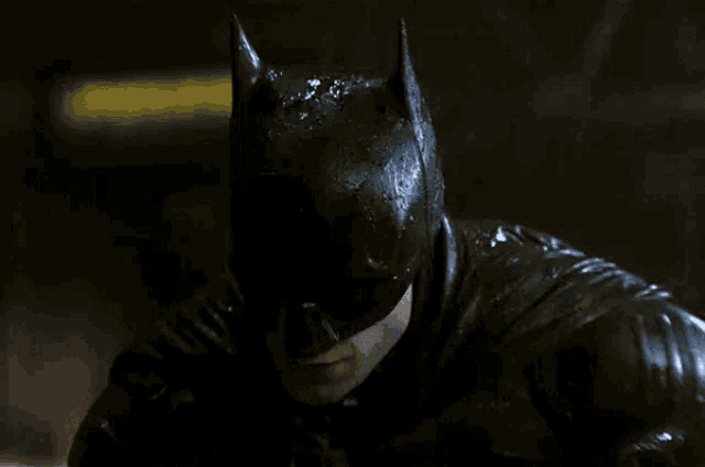a close up of a man in a batman costume with water dripping from his face .