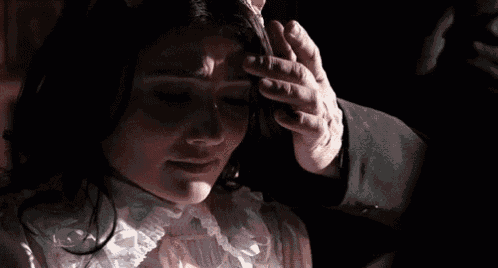 a man is touching a woman 's forehead with his hand .