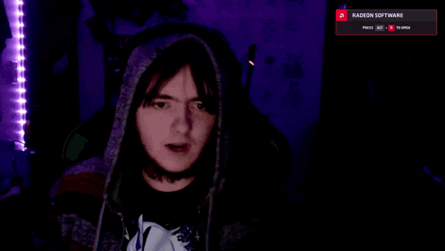 a man wearing a hoodie is looking at a screen that says radeon software at the top