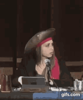 a woman in a pirate hat is sitting at a table with a microphone