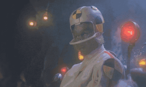 a man wearing a helmet is giving a thumbs up in front of a red light