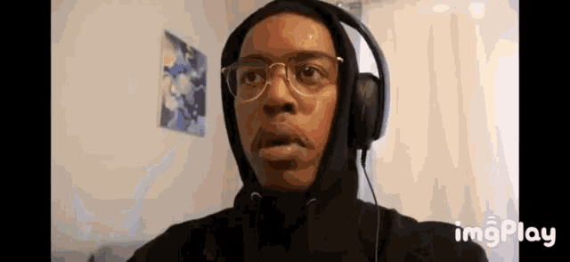 a man in a hoodie and headphones is making a funny face .