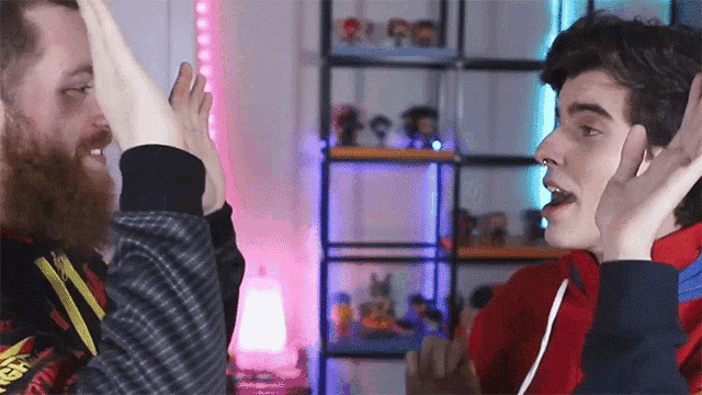 two men are giving each other a high five in front of a shelf with figurines on it