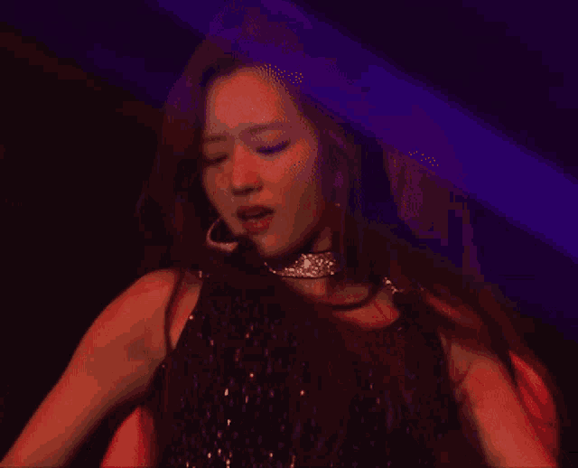 a woman is dancing in a dark room with a purple light behind her